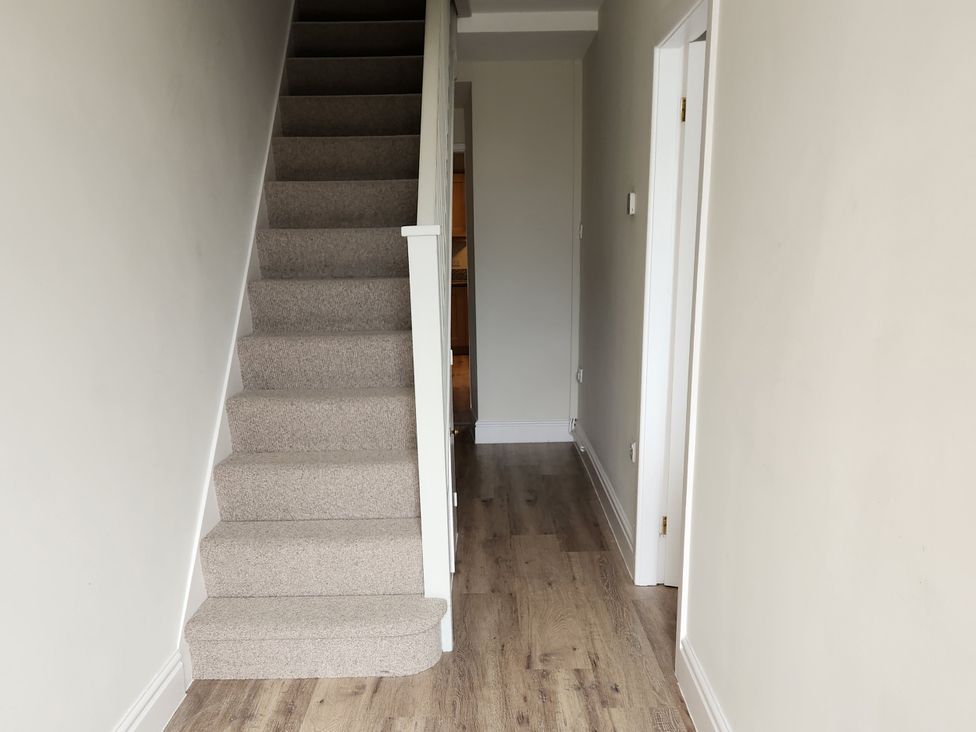 A hallway with stairs and doorways at 8 Arvonia Terrace Cricieth