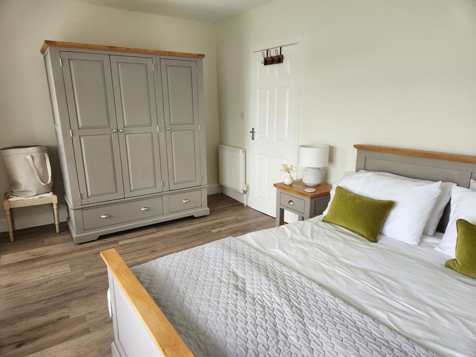 A bedroom with a bed and wardrobe at 8 Arvonia Terrace in Cricieth
