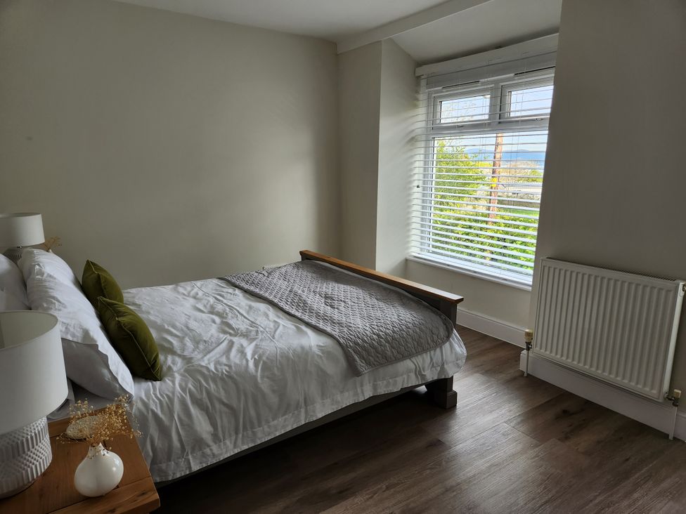 A bedroom with a bed and window at 8 Arvonia Terrace Cricieth