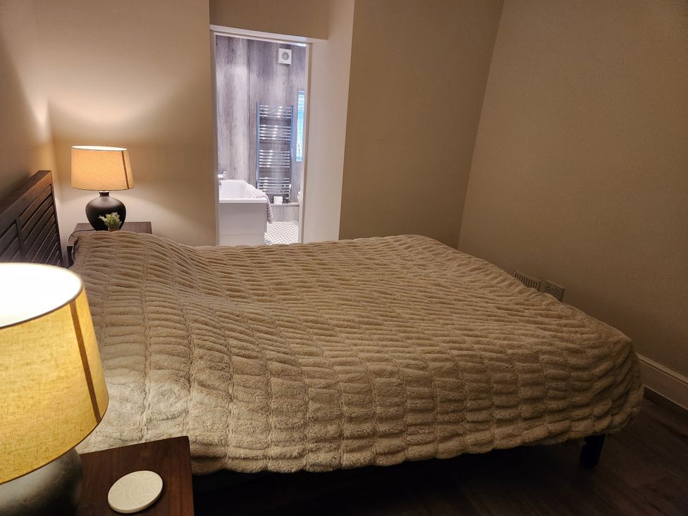 A bedroom with a bed and a lamp at 8 Arvonia Terrace in Cricieth
