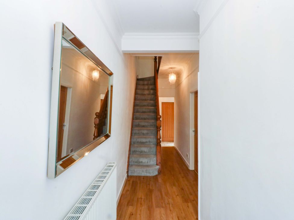 A hallway with a staircase and mirror at Y Berth in Caernarfon
