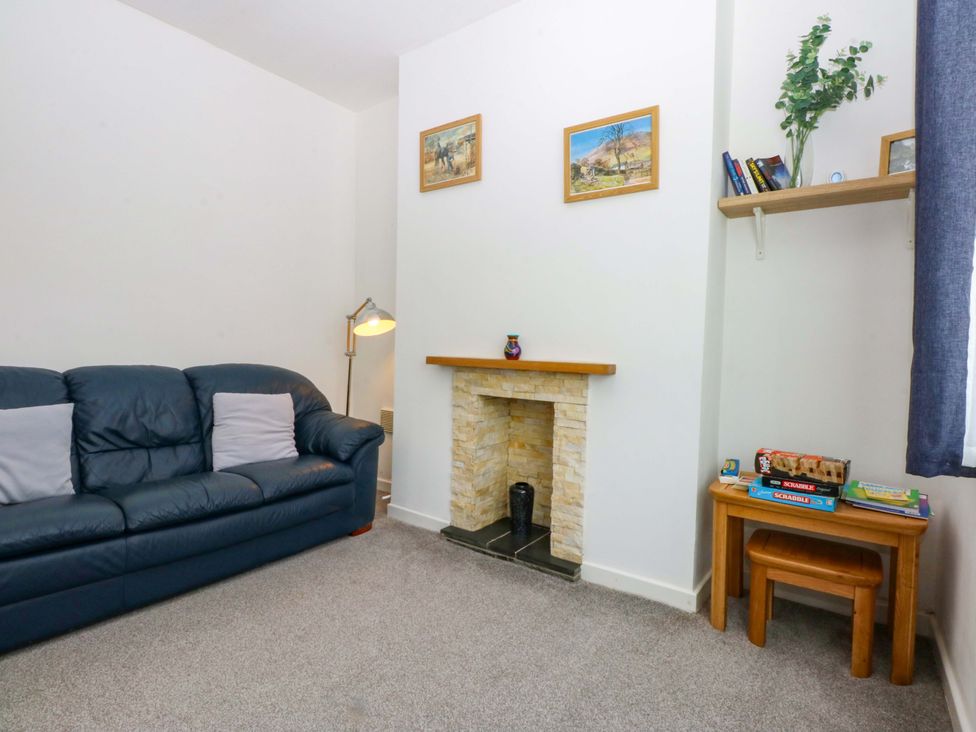 A living room with a sofa, lamp, fireplace, and bookshelf at Y Berth in Caernarfon