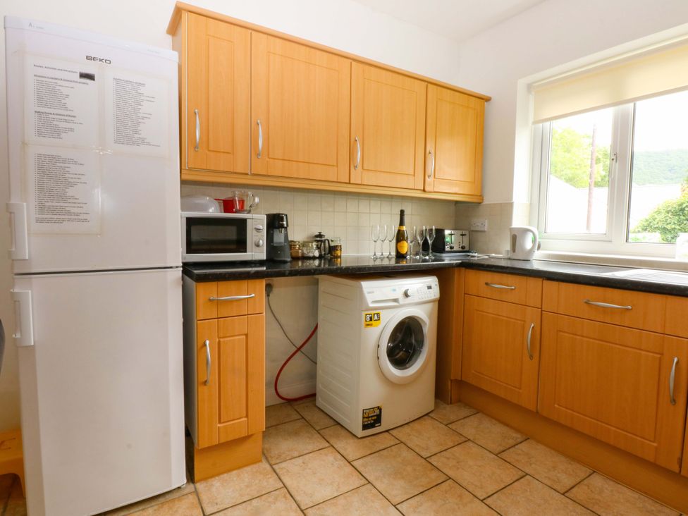 A kitchen with a washing machine and refrigerator at Y Berth Caernarfon