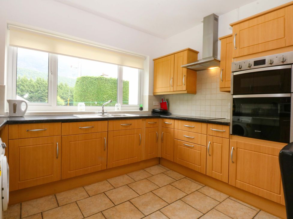 A kitchen with wooden cabinets and appliances at Y Berth in Caernarfon