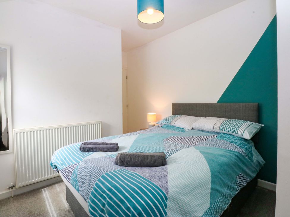 A bedroom with a bed and bedside lamp at Y Berth Caernarfon