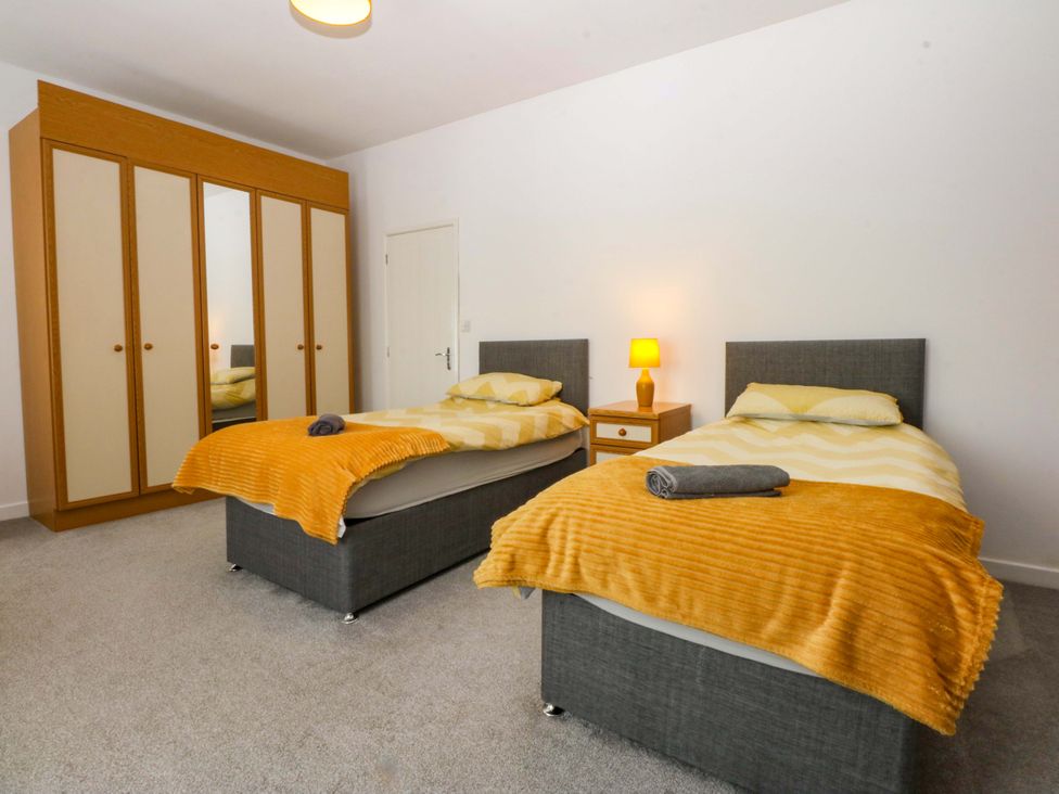 A bedroom with two beds and a wardrobe at Y Berth in Caernarfon