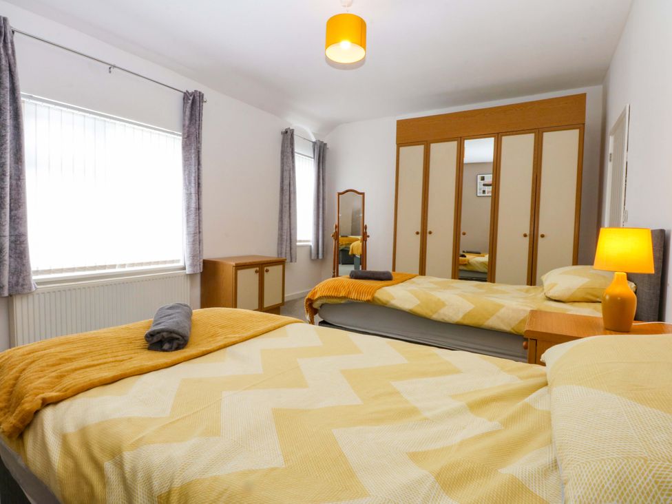 A bedroom with two beds and a wardrobe at Y Berth in Caernarfon