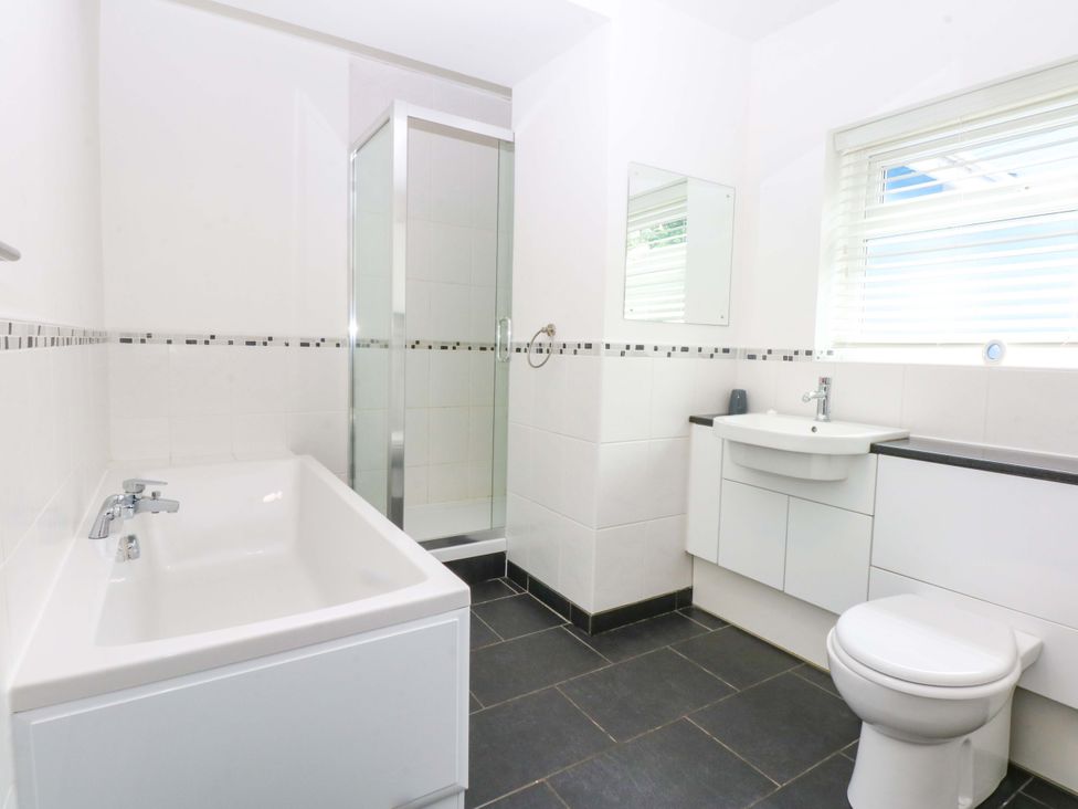 A bathroom with a bathtub, shower, sink, and toilet at Y Berth Caernarfon