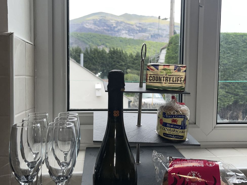 A kitchen with a champagne bottle and glasses near a window at Y Berth in Llanberis