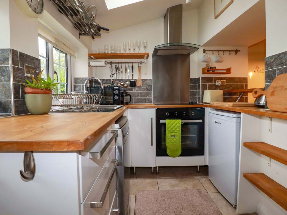 A kitchen with a stove, fridge, and sink at Woodview in Looe
