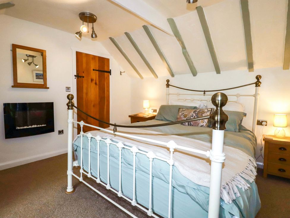 A bedroom with a bed and a fireplace at Woodview in Looe