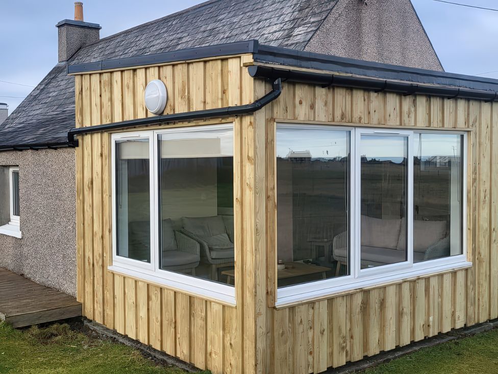 An outdoor photo of a wooden-clad structure with large windows at Fisherman’s Holding Port Of Ness