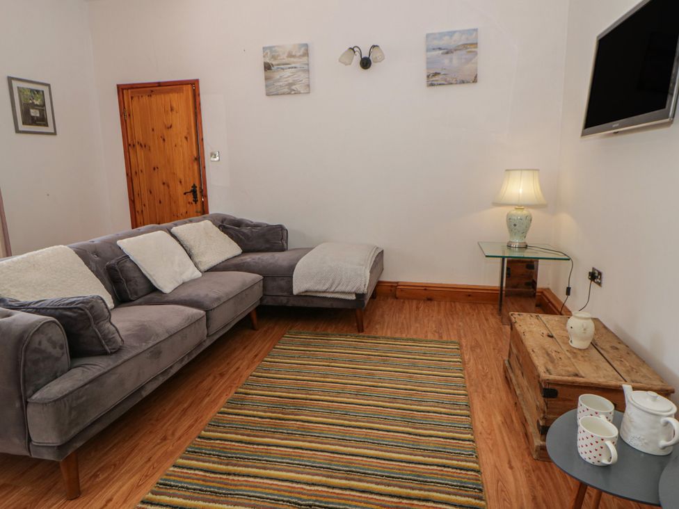 A living room with a sofa and a table at Swallows Retreat in Tenby