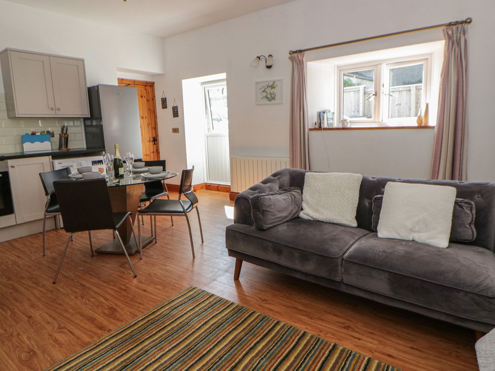 A living room with a sofa and dining table at Swallows Retreat in Tenby