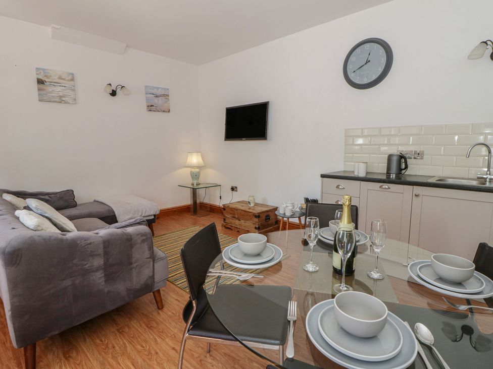 A living room with a dining area and kitchen unit at Swallows Retreat in Tenby