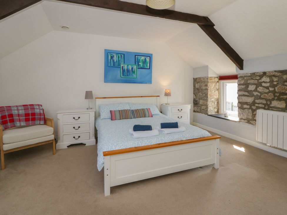 A bedroom with a bed and armchair at Swallows Retreat in Tenby