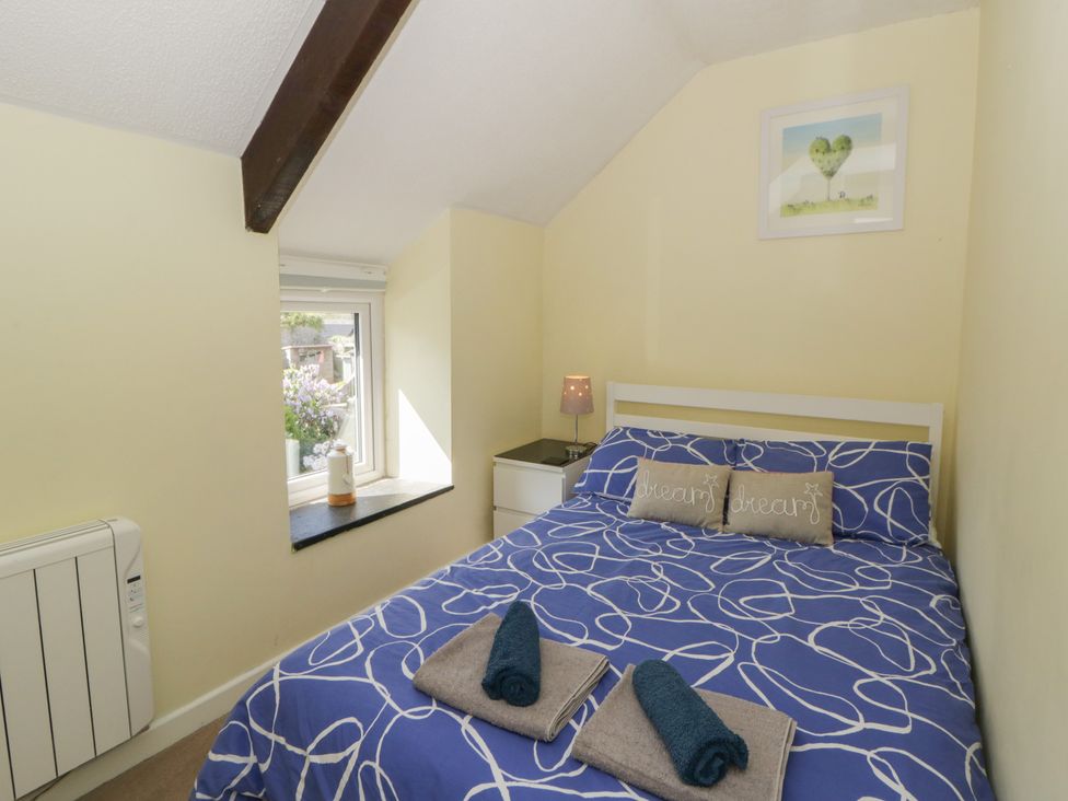 A bedroom with a bed and window at Swallows Retreat in Tenby