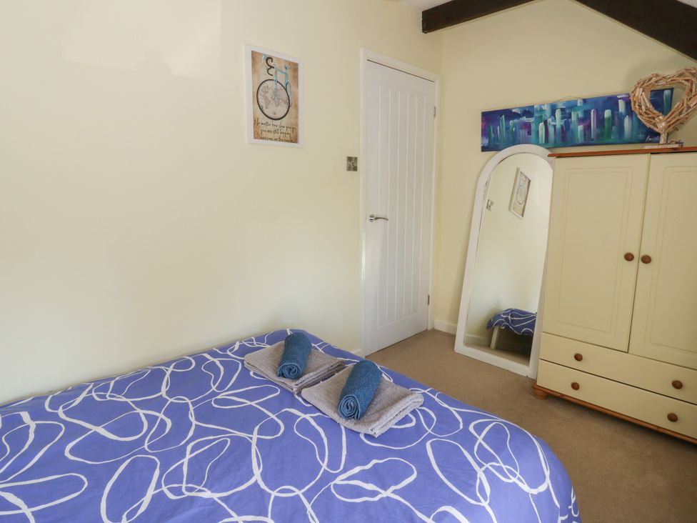 A bedroom with a bed and a wardrobe at Swallows Retreat in Tenby