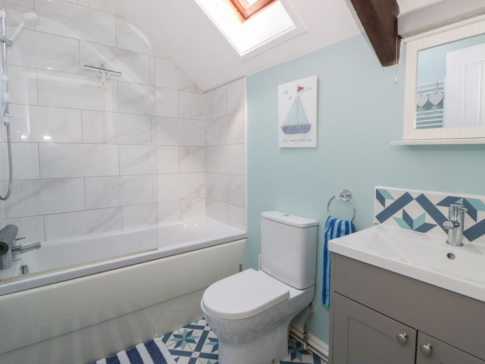 A bathroom with a bathtub, toilet, and sink at Swallows Retreat in Tenby