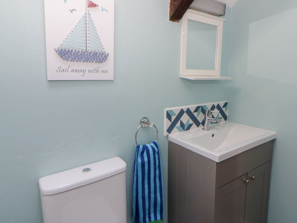 A bathroom with a sink, toilet, and wall art at Swallows Retreat in Tenby