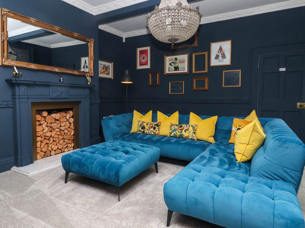 A living room with a blue sofa and wooden fireplace at Kexby House