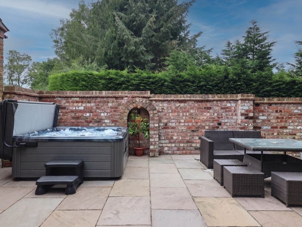 An outdoor area with a hot tub and seating at Kexby House