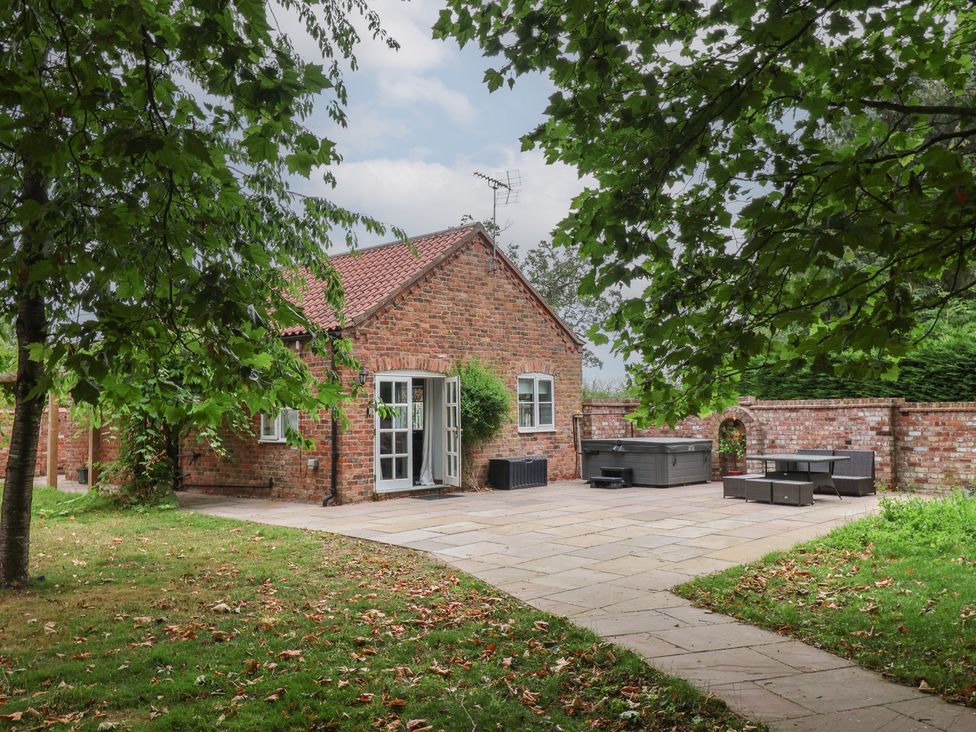 An outdoor area with a brick house and seating at Kexby House in Kexby near Wilberfoss