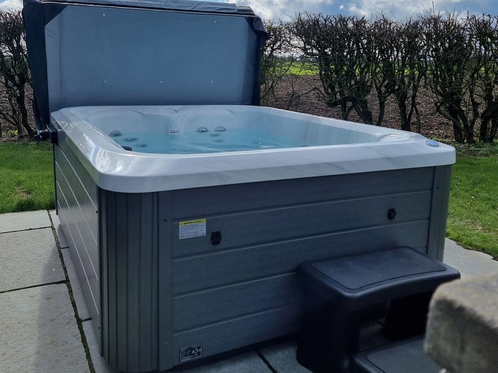 A hot tub on a patio with a step at Wren in Huggate near Bishop Wilton