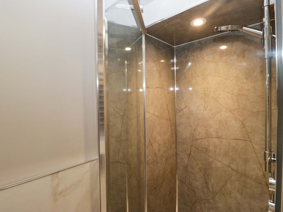 A shower with glass door and stone walls at Beckmead in Windermere