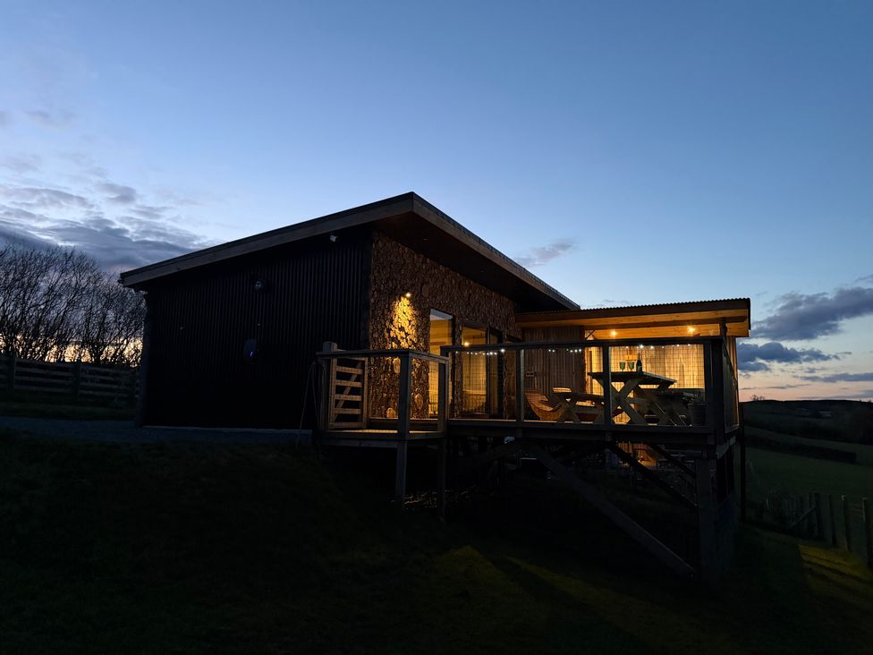 A cabin with a deck and outdoor seating at Bryn Hafod in Llandrindod Wells