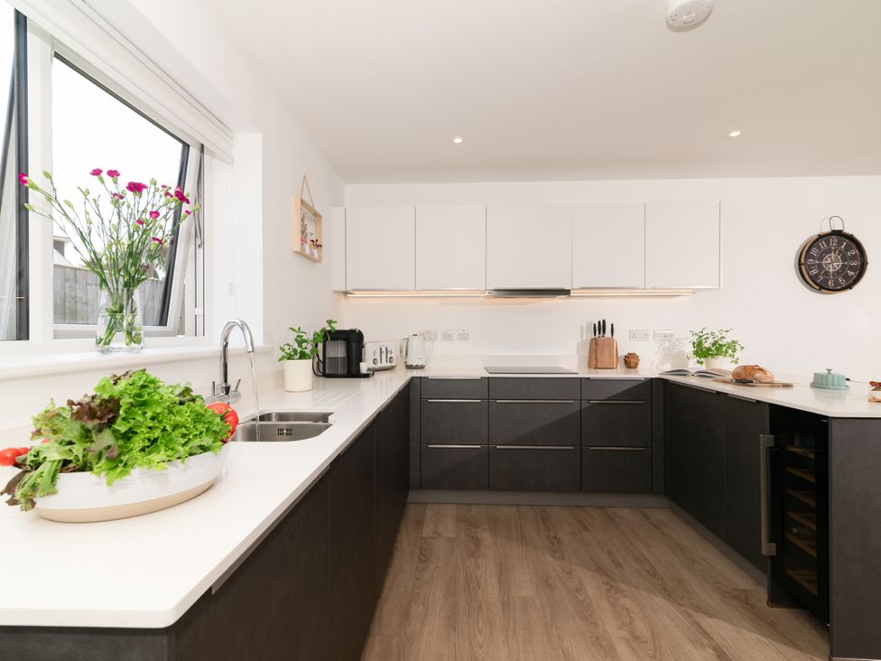 A kitchen with a sink, cabinets, and vegetables at Sandy Cove in Praa Sands