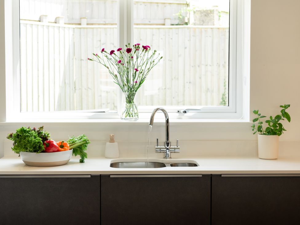 A kitchen with a sink and vegetables on the countertop at Sandy Cove in Praa Sands