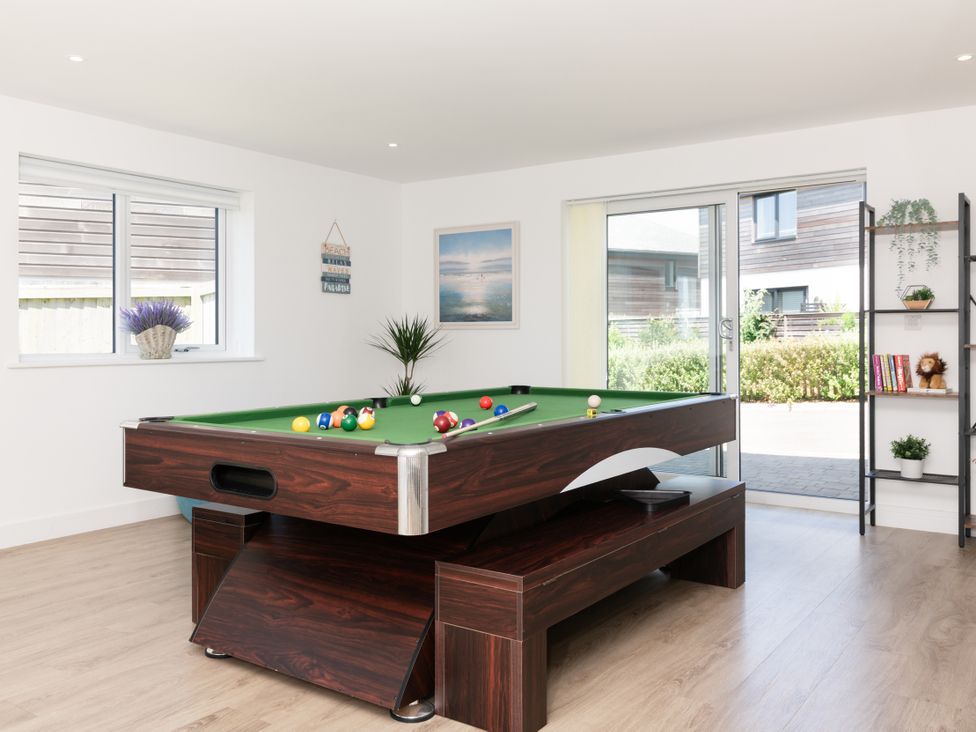 A game room with a pool table and books on a shelf at Sandy Cove in Praa Sands