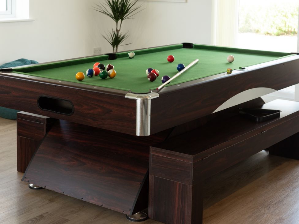A pool table with billiard balls and a cue stick at Sandy Cove in Praa Sands