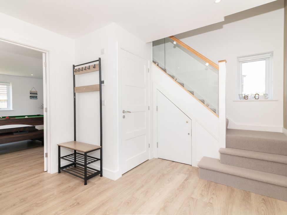 A hallway with a staircase and a coat rack at Sandy Cove in Praa Sands