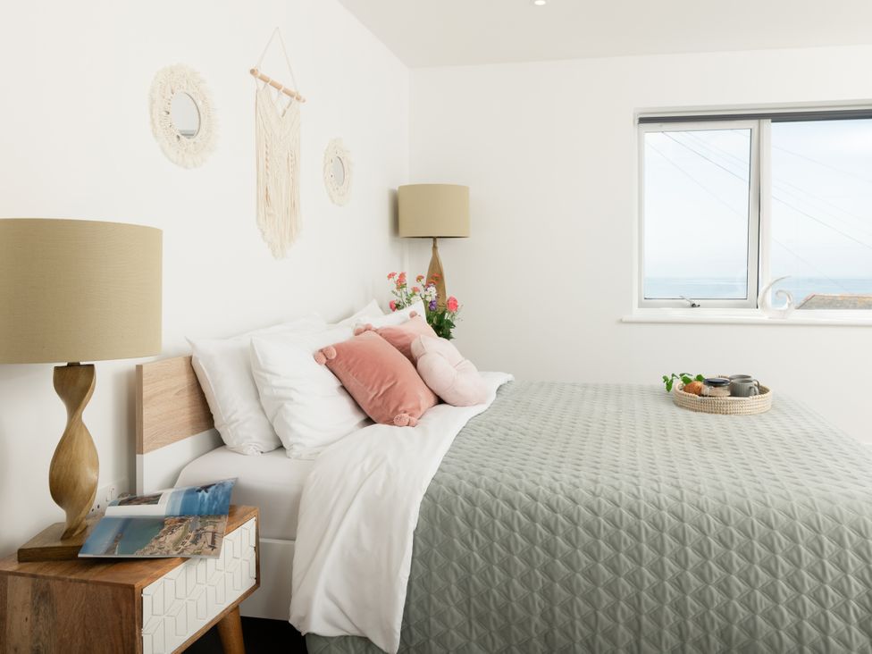 A bedroom with a bed and nightstand at Sandy Cove in Praa Sands