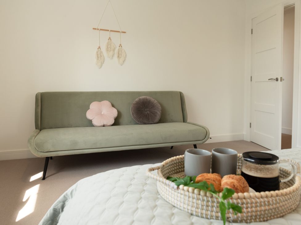 A living room with a green sofa and coffee tray at Sandy Cove in Praa Sands