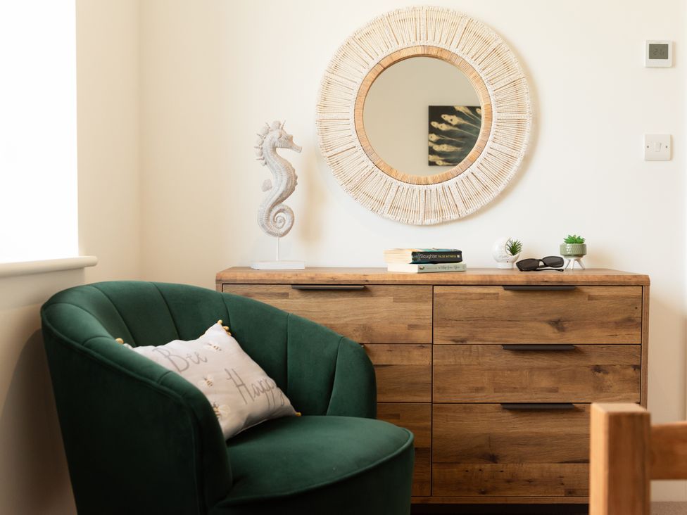 A living room with a green chair and wooden cabinet at Sandy Cove in Praa Sands