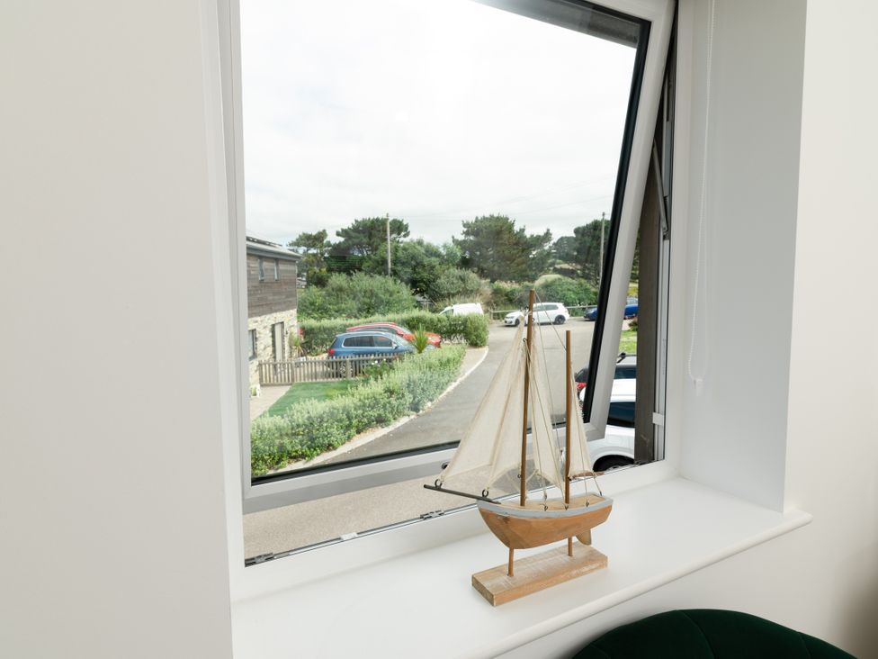 A living room with a sailboat on a windowsill at Sandy Cove in Praa Sands
