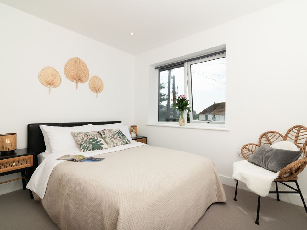 A bedroom with a bed and decorative wall pieces at Sandy Cove in Praa Sands