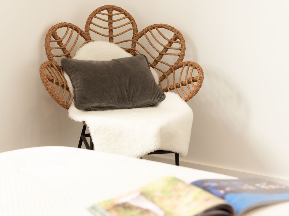 A chair with a cushion and blanket in a living room at Sandy Cove in Praa Sands