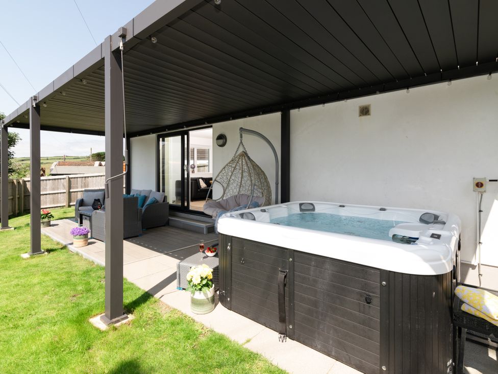 An outdoor area with a hot tub and seating at Sandy Cove in Praa Sands