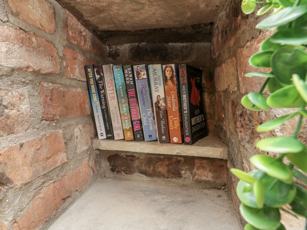 A collection of books on a shelf with a plant at Betsy's Burrow