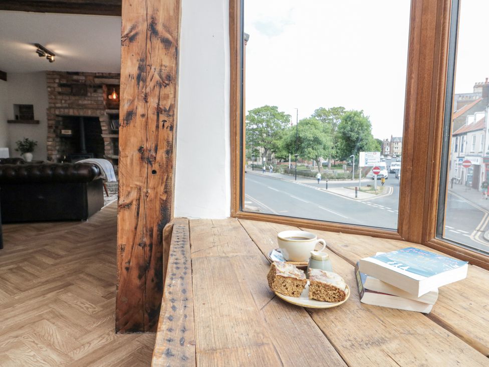 A living room with a window, table, coffee cup, and books at Betsy's Burrow