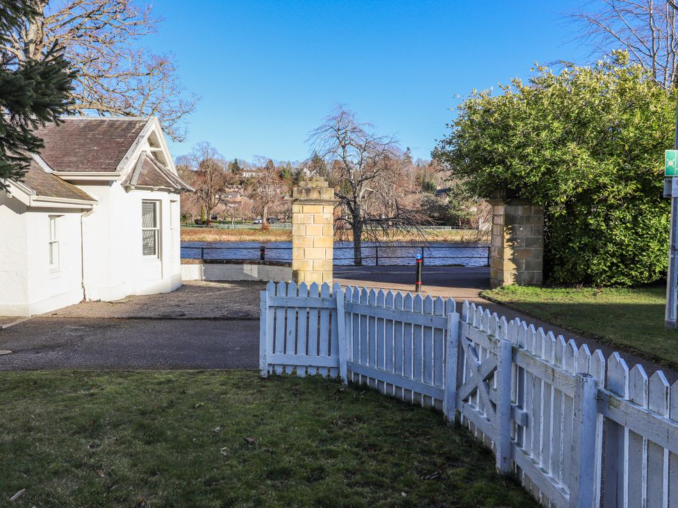 A view of a house and fence with a river in the background at Porter's Lodge Inverness