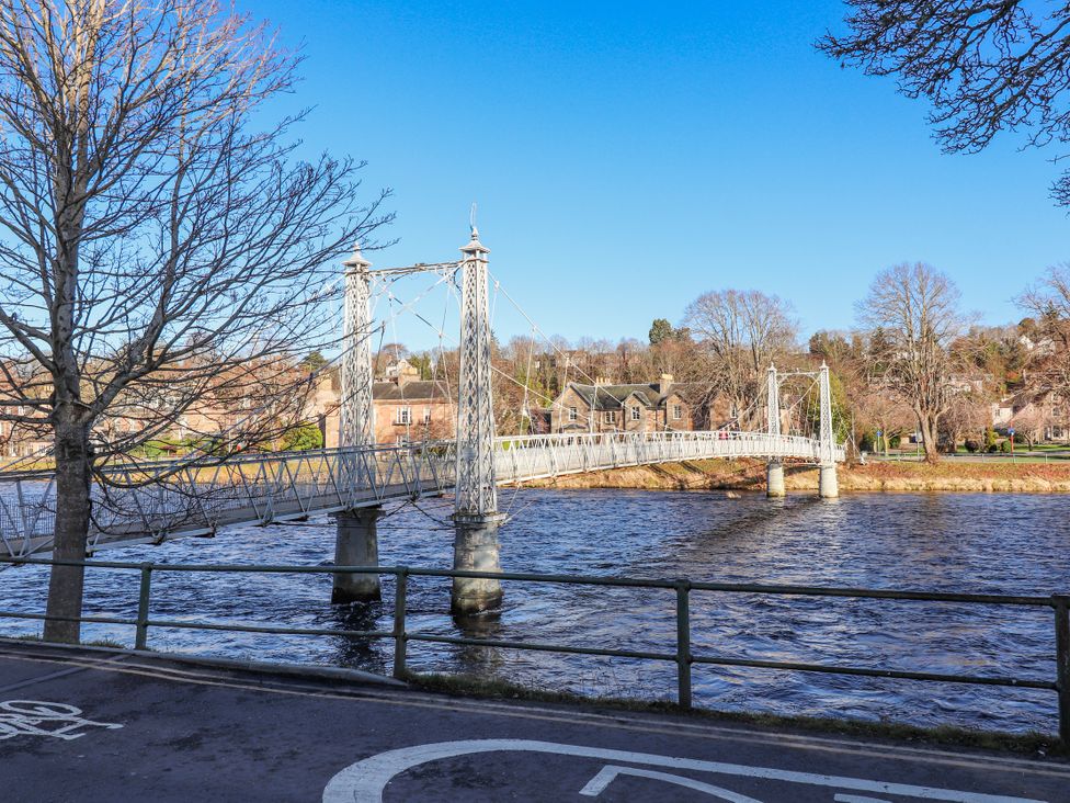 A bridge over a river with trees and houses at Porter's Lodge in Inverness