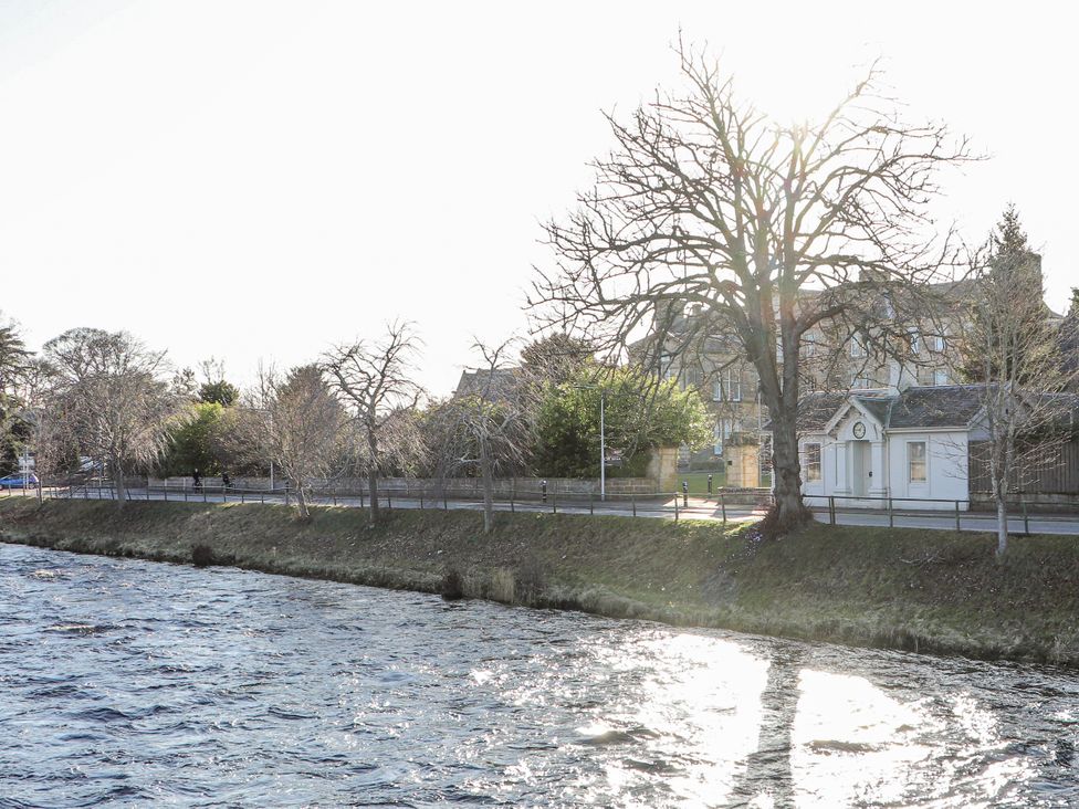 A river with a tree and a building at Porter's Lodge Inverness