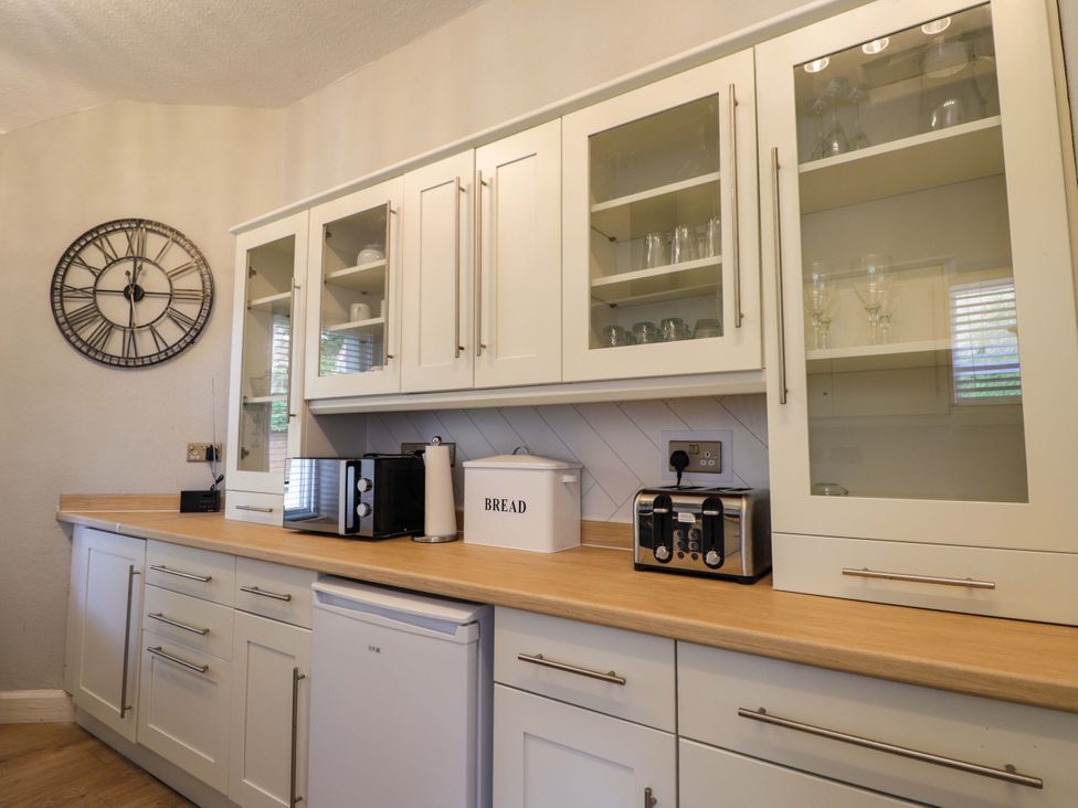 A kitchen with white cabinets and appliances at Porter's Lodge in Inverness