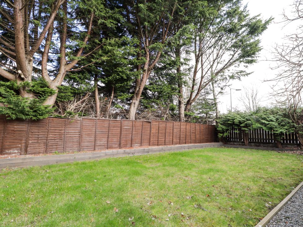 A garden area with a fence and trees at Porter's Lodge in Inverness
