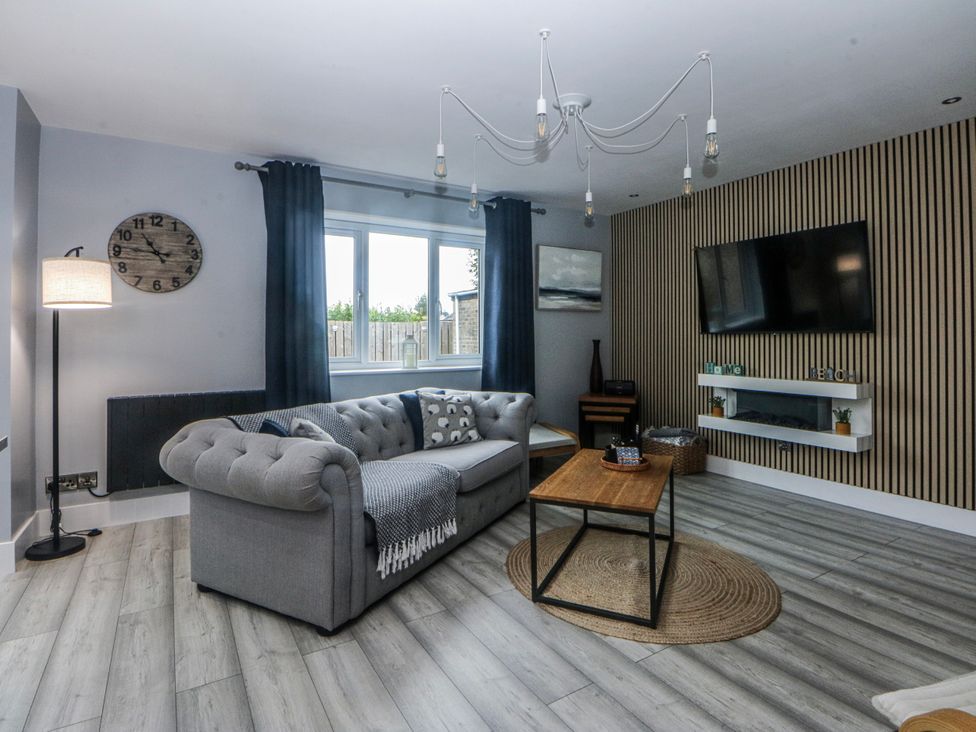 A living room with a couch, lamp, and television at Ty Glan Morfa in Morfa Bychan